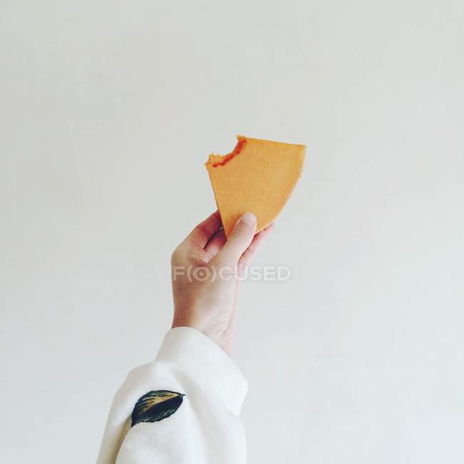 Human hand holding pumpkin slice against white background — Stock Photo