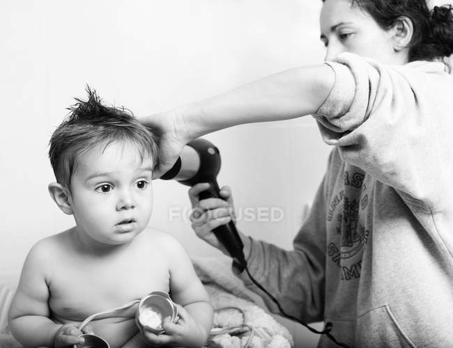 Мати сушить маленького сина після ванни з фен — стокове фото