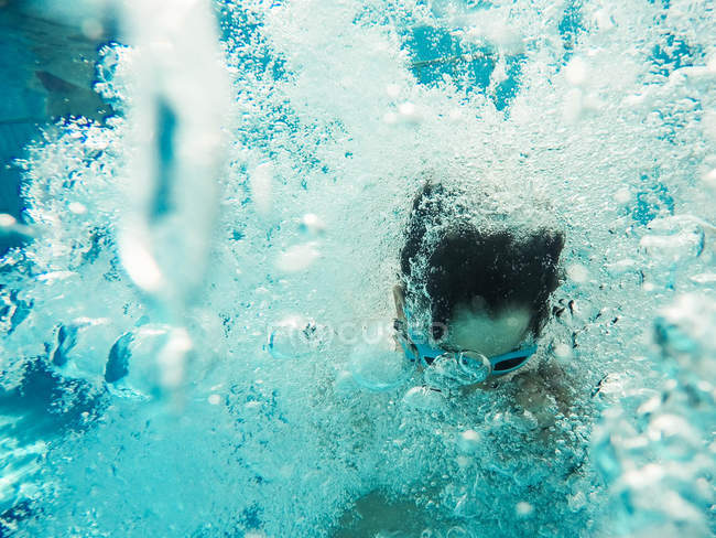 Подводный вид мальчика, прыгающего в бассейн — стоковое фото