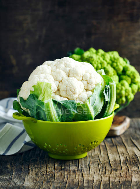 Fresh cauliflower in a colander on wooden table — Stock Photo