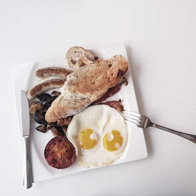 Assiette avec élégant petit déjeuner anglais sur table blanche — Photo de stock