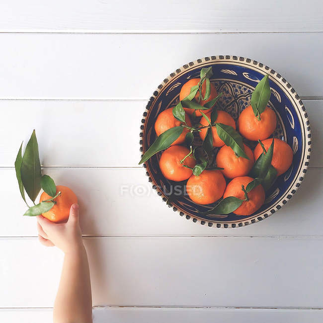 Abgeschnittenes Bild einer Jungenhand, die eine Clementine aus einer Schüssel nimmt — Stockfoto