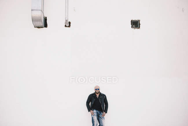 Homem legal de pé na frente da parede branca — Fotografia de Stock