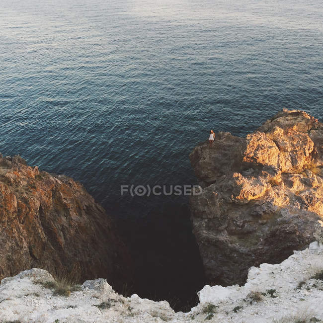 Молода жінка стоїть на скелі на узбережжі моря — стокове фото