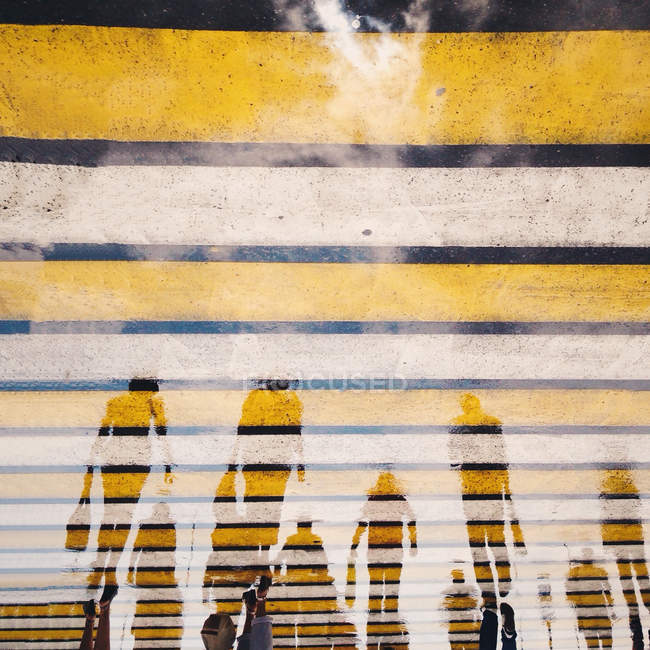 Abgeschnittenes Bild von Spiegelungen von Menschen, die im Wasser auf der Straße gehen — Stockfoto