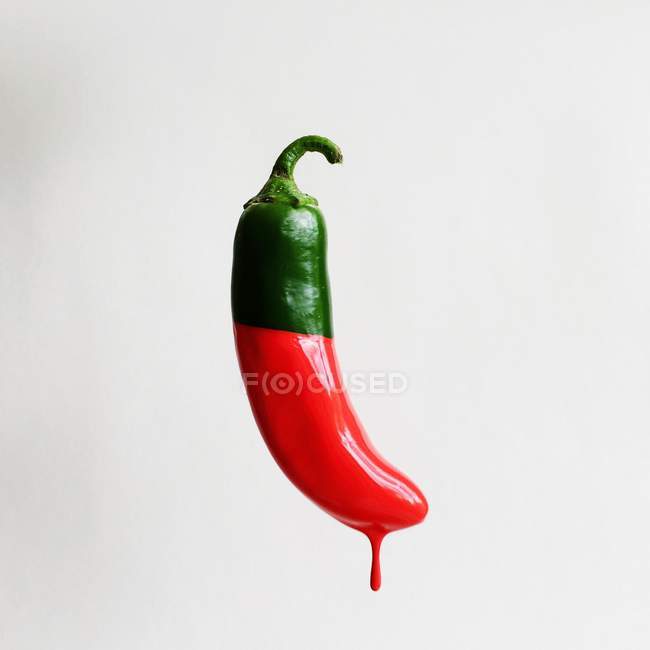 Green chill dipped in red paint against white background — Stock Photo