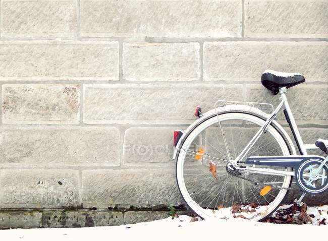 Fahrrad im Schnee an Wand gelehnt — Stockfoto