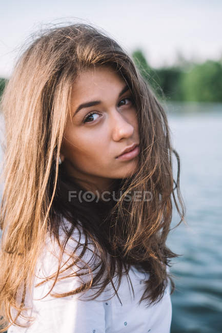 Retrato de una mujer con el pelo castaño mirando por encima del hombro - foto de stock