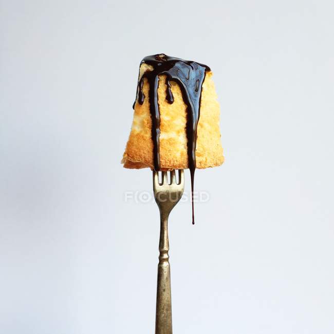 Pastel de esponja en tenedor sumergido en chocolate - foto de stock