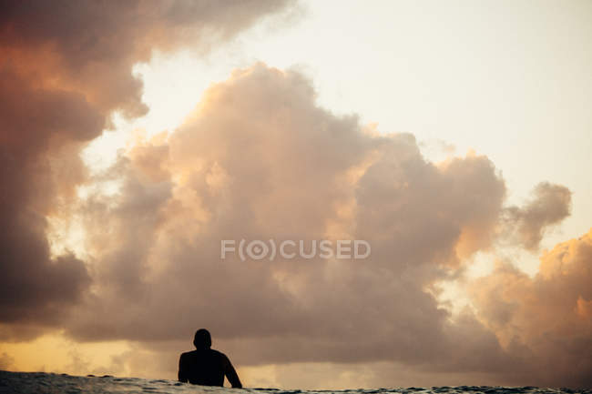 Silhueta de surfista esperando para pegar uma onda sob céu nublado — Fotografia de Stock