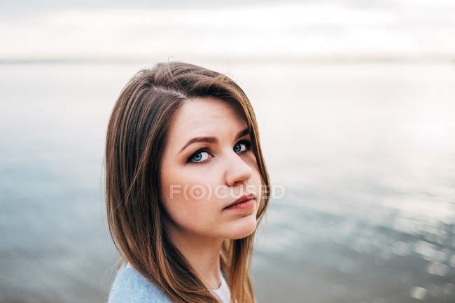 Retrato de mulher com cabelo castanho em pé em frente ao mar — Fotografia de Stock