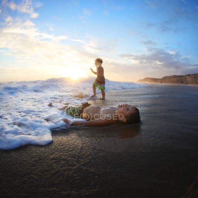 Deux garçons caucasiens passer du temps sur la plage de l'océan — Photo de stock