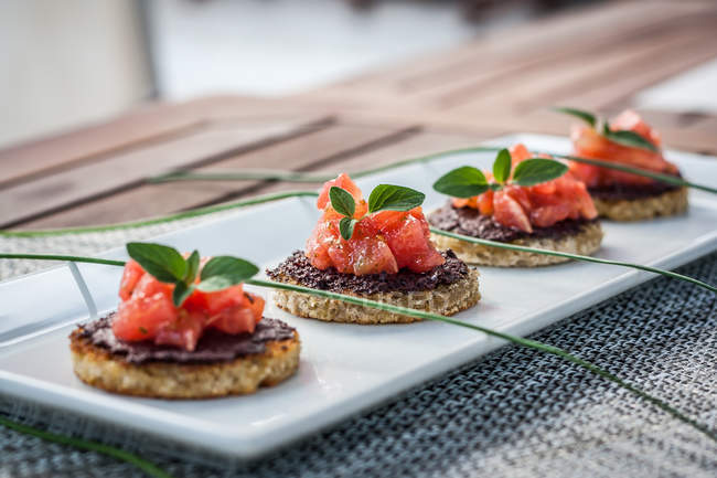 Помидоры и оливковая брускетта блюдо на белой тарелке — стоковое фото
