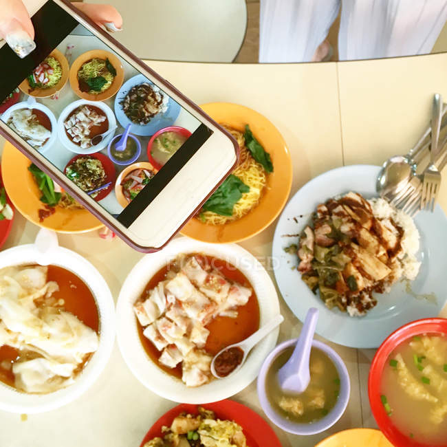 Женщина фотографирует еду с помощью мобильного телефона — стоковое фото