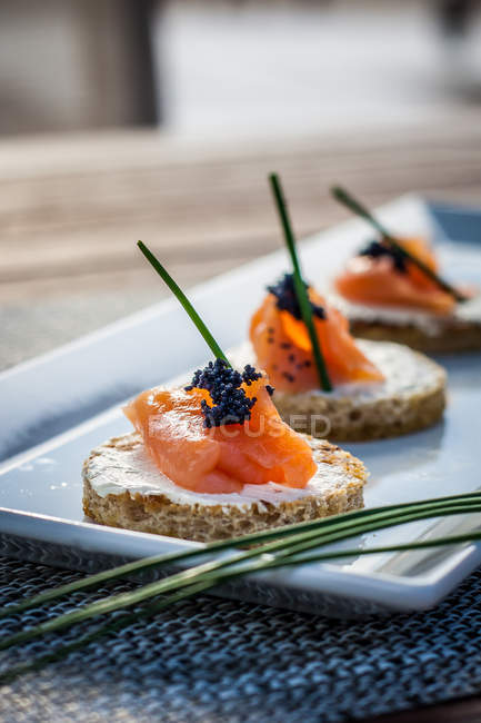 Canapes with smoked salmon and cream cheese, blurred background — Stock Photo