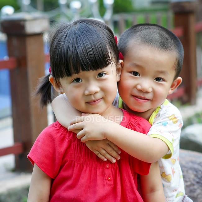 Портрет маленьких азіатських дітей, що обіймаються і дивляться на камеру — стокове фото