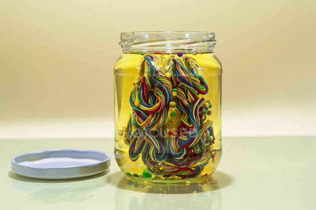 Conceptual brain in glass jar of oil made from multi-colored wires — Stock Photo