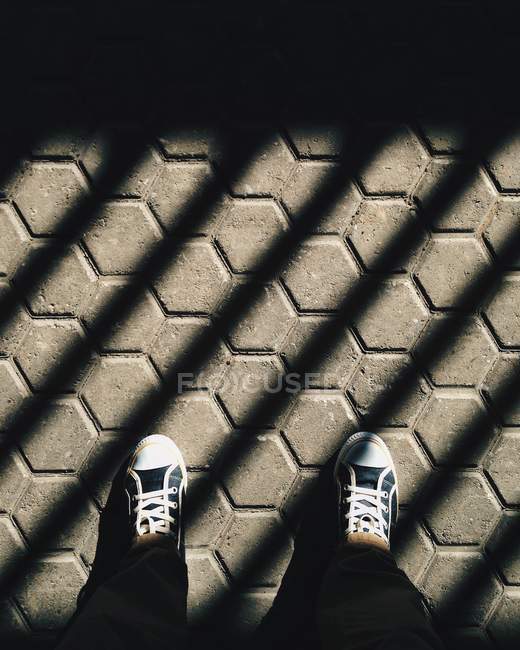 Cropped image of male feet standing in shadows, pov — Stock Photo