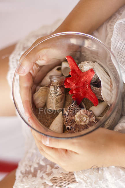 Cropped image of Girl holding seashell collection in glass jar — Stock Photo