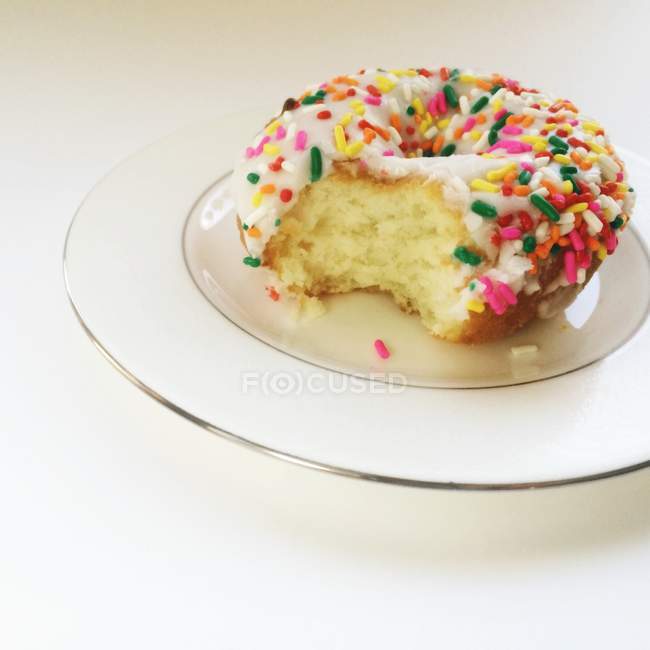 Donut on a plate with a bite taken out of it — Stock Photo