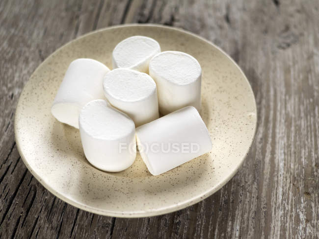 Pilha de marshmallows em uma placa sobre fundo de madeira — Fotografia de Stock