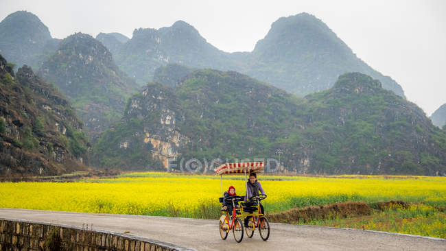 Madre e hija en bicicleta juntas, Yunnan, China - foto de stock