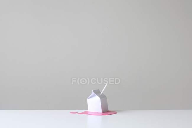 Conceptuel carton de lait blanc avec de la paille blanche sur une piscine de lait de fraise rose — Photo de stock