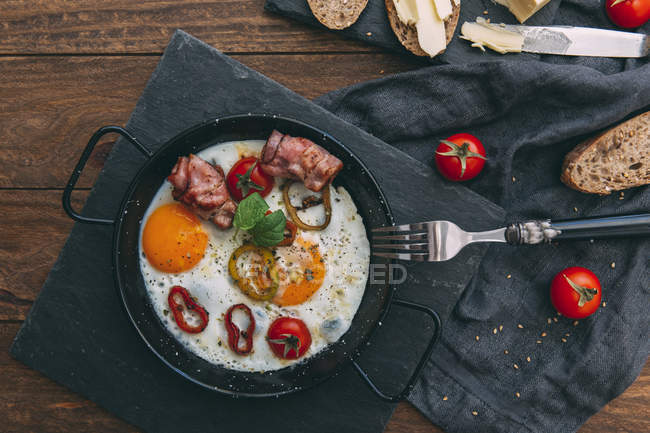 Ovos fritos, bacon e tomate cereja com pão — Fotografia de Stock