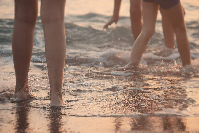 Immagine ritagliata delle gambe nelle onde del mare — Foto stock