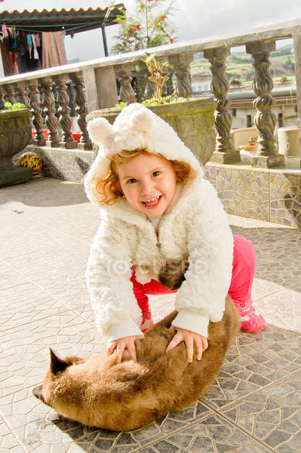 Girl playing with ginger cat on terrace — Stock Photo