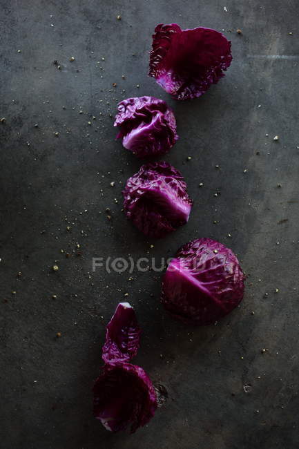 Feuilles de chou rouge fraîches en rangée sur une surface sombre — Photo de stock