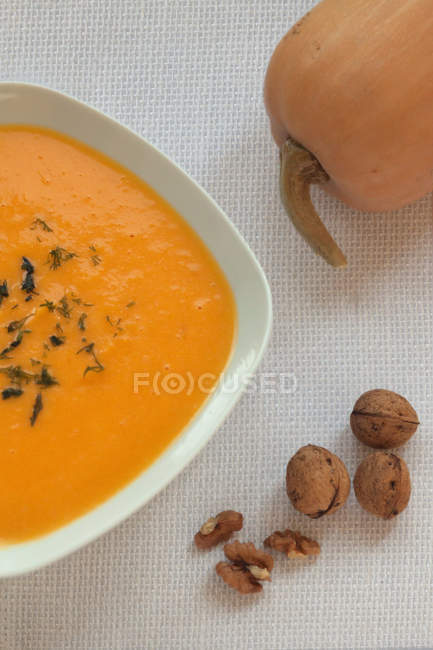 Миска гарбузового супу і горіхів над столом — стокове фото
