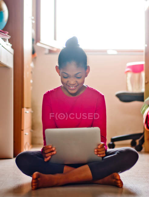 Девушка сидит на полу с цифровым планшетом — стоковое фото