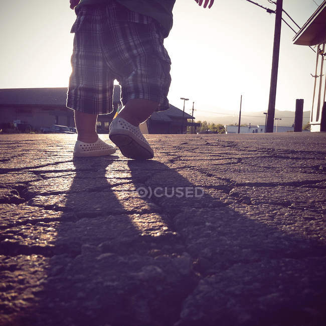 Низька секція маленького хлопчика, що йде вулицею — стокове фото