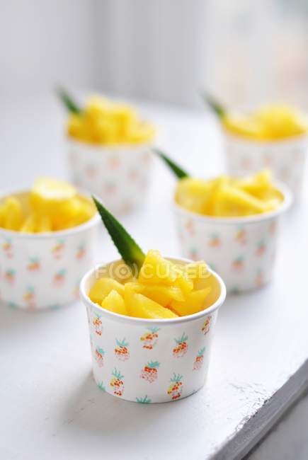 Five paper cups filled with pineapple chunks — Stock Photo