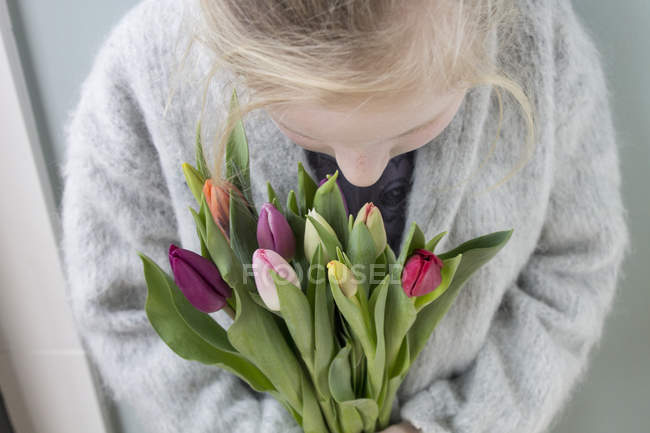 Крупным планом маленькая девочка держит кучу тюльпанов — стоковое фото
