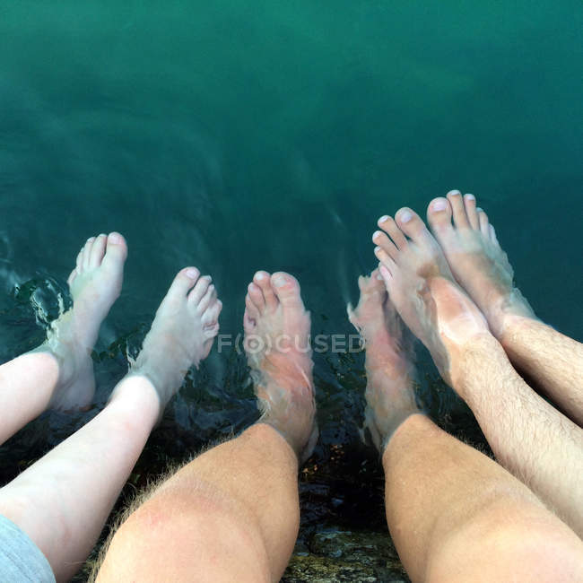 Immagine ritagliata di tre uomini con i piedi in acqua — Foto stock