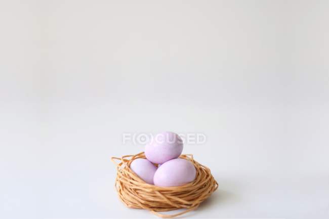 Sugar coated chocolate eggs in a string nest — Stock Photo