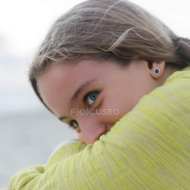 Close-up de Sorrindo menina abraçando seus joelhos e olhando para o lado — Fotografia de Stock