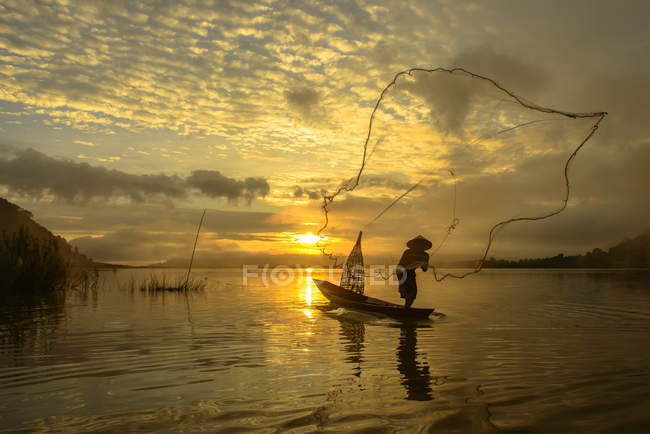 Silhouette d'un homme lançant un filet de pêche, Lac Bangpra, Thaïlande — Photo de stock
