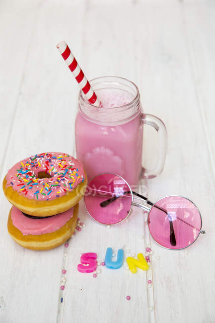 Donuts rosados, gafas de sol rosadas y batido de fresa - foto de stock