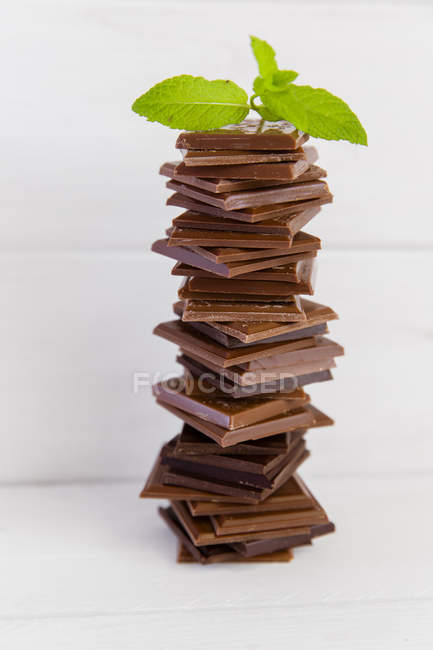 Стек шоколадних скибочок з м'ятою над дерев'яним столом — стокове фото