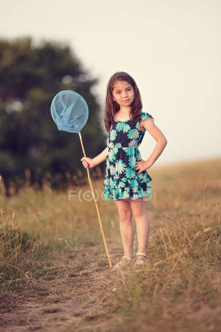 Chica sosteniendo una red de mariposas en el campo - foto de stock