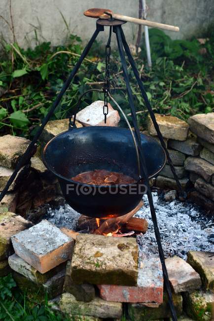 Preparation process of traditional hungarian goulash in pot hanging over a fire — Stock Photo