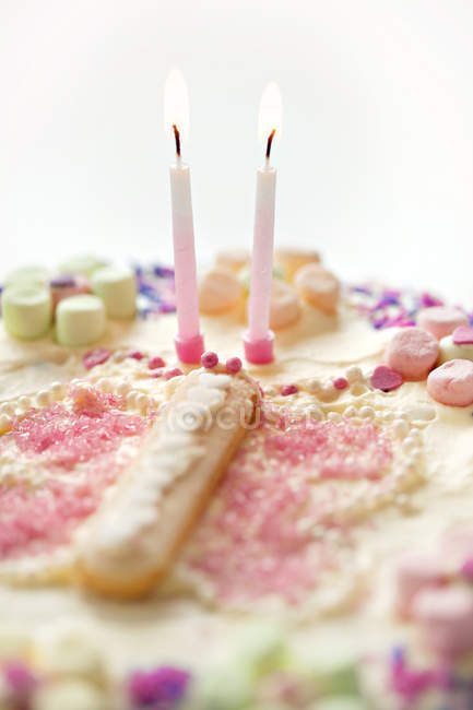 Вкусный красочный праздничный торт с двумя свечами — стоковое фото