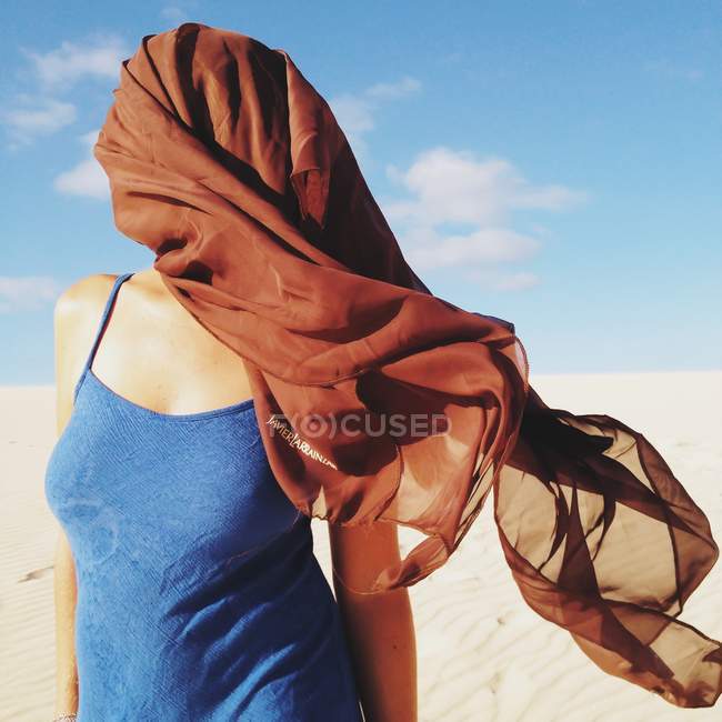 Mujer con la cara cubierta bufanda de pie sobre la arena — Stock Photo