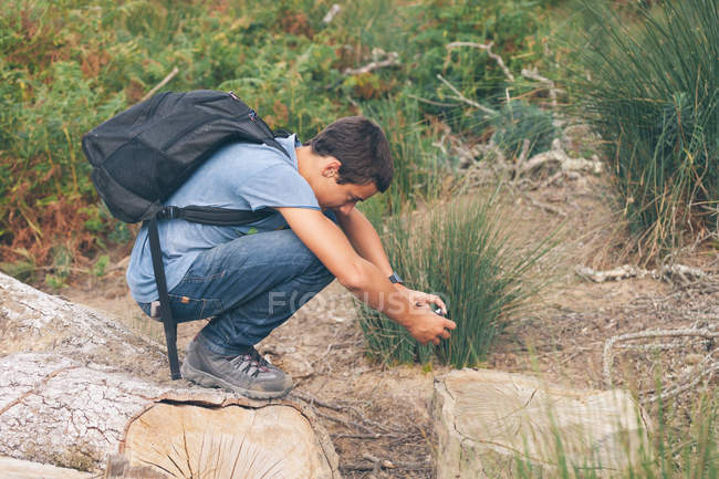 Boy crouching to take photo in woodland — Stock Photo