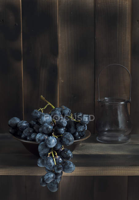 Bando de uvas vermelhas na tigela na mesa — Fotografia de Stock