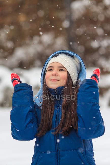 Glückliches Mädchen mit Händen in der Luft beim Spielen im Schnee — Stockfoto