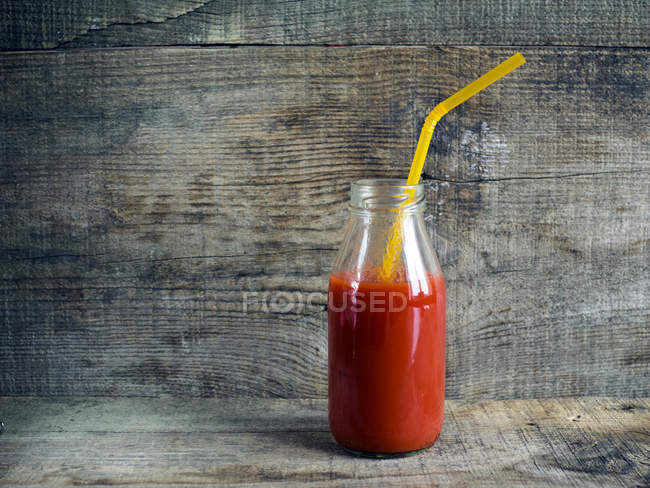 Tomato juice in glass bottle with straw — Stock Photo